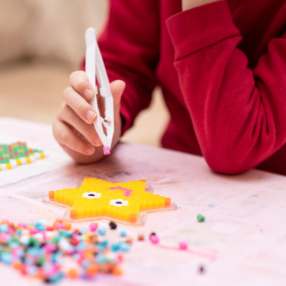 Little,Girl,Holds,A,Tweezers,With,Bead,,Creates,Art,Toy